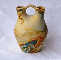 Front view of the Nedano double-flute pottery vase showing the marbled swirl color pattern and circular handle connecting the two fluted spouts.
