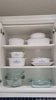 White cabinet shelves with various casserole dishes and glass bowls, showing the full set.