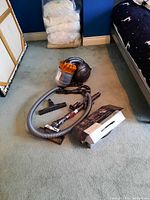 Vacuum and all accessories laid out on carpeted floor