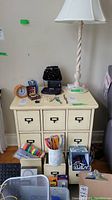 Front view of Ethan Allen 9-cubby distressed wood cabinet with items on top and office supplies in front