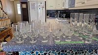 Various sizes of clear Kosta Boda drinking glasses arranged on countertop