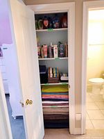 Closet with shelving containing linens folded and toiletries organized on shelves.