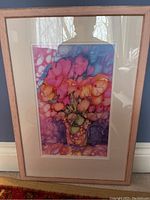 Photo of framed, matted watercolour painting with vibrant flowers in a vase with wooden frame and cream mat.
