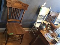 Overview of two antique pressed back chairs beside a white chair (white chair not included)