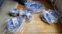 Overview of stacks of Spode Italian pattern dinner plates, side plates, saucers and teacups on wood floor, some wrapped in plastic
