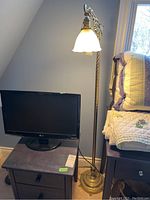 Full view of metal floor lamp next to nightstand and monitor