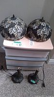 Pair of stained glass lamp shades and two metal lamp bases displayed