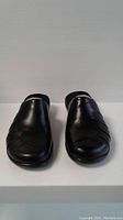Front view of the Clarks black leather slip-on shoes showing smooth toe surface and black color.