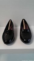 Front view of black patent loafer-style Clarks ladies shoes, size 6.5XW, new condition with shoe supports inside.