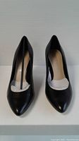 Front view of the black pointed toe high heel shoes showing size and new condition with paper stuffing intact in original packaging.