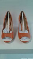 Front view of the orange Franco Sarto peep toe shoes showing the open toe design and interior brand stamp.