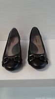 Front view of the pair of new black Hush Puppies ladies shoes showing the metal bit decoration and rounded toe design.