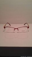 Front view of the Inspira eyeglass frames showing the red semi-rimless front and clear lenses.