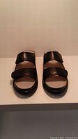 Front view of pair of black leather slide sandals showing open toe and two straps.