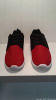 Front view of men's athletic shoes showing red mesh toe area and black laces
