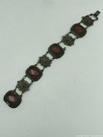 Full view of the bracelet showing the alternating filigree floral links and pink stone settings resting flat.