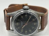 Close-up image of the Clebar watch face showing the black dial, Arabic numerals, and crown.