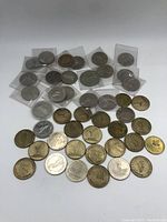 Overview of the coin and token lot arranged on a surface showing various metallic coins including Canadian Loonies and tokens.