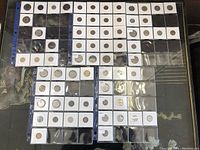 Overview of vintage and antique coins in protective holders arranged in plastic sleeves showing a wide variety of coins.