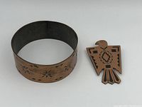 Photo showing copper cuff bracelet with stamped stars and solid silver bird pin side by side