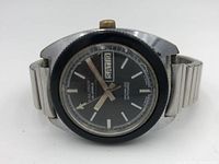 Front angled view of Kaltron watch showing black dial, silver hour markers and hands, black bezel, and stainless steel band with visible wear.