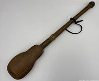 Full view of vintage wooden opium scale with long handle and broad paddle end.