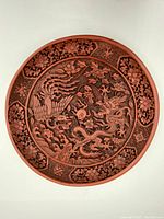 Top view of the red Asian carved decorative plate showing dragon, phoenix, and floral motifs.