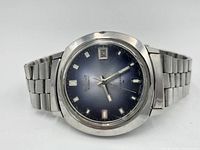 Front view of Seiko automatic wristwatch showing blue gradient dial with silver-tone luminous indices and date window at 3 o'clock.
