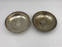 Top view of two round silver coin bowls showing interior