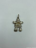Front view of one silver Inukshuk pendant showing stacked stone-like shapes and loop for chain, marked Scott Ster.