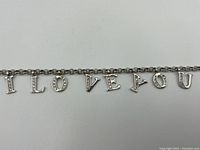 Close-up image of the bracelet's letter charms spelling 'I LOVE YOU' with small gemstones set in letters.