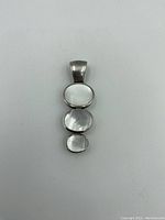 Front view of the sterling silver pendant with three mother of pearl stones arranged vertically from largest to smallest.