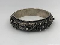 Side view of sterling silver tribal bracelet showing floral and beaded designs with oxidized detailing.
