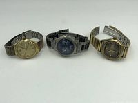 Three vintage watches displayed side by side showing front view and bands.