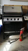 Front view of Premier Ultra Chef convertible BBQ grill showing the cooking hood, four knobs, and rotisserie spit attachment on the ground.