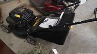 Photo of Yardworks 21-inch gas powered push lawn mower showing side view with attached grass collection bag and rear wheels visible.