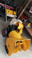Front-left view showing yellow auger housing, chute and black control handles