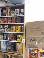 Wide shelving unit with various cans of paint, stain, sealants and adhesives.