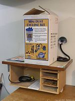 Blue Tornado Mini Dust Cyclone Kit boxed with illustrations and specifications, placed on the router table, showing accessories and kit contents.