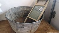 Galvanized metal tub with washboard standing inside, showing tub size and condition.