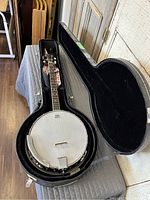 Open hard case with 4-string banjo and strap inside