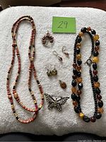 Amber and silver assorted jewellery including necklaces, earrings, brooch, and ring laid out on white fabric.