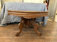 Full view of the antique wooden coffee table showing the tabletop, rounded edges and carved detail at base.
