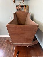 Front view of the solid wood antique cradle showing curved rocking base and simple wooden panels.