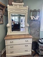 Front view of the antique dresser with attached mirror, showing three drawers and ornate mirror frame with carved wood details.