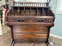 Front view showing carved fretwork panel above two lower drawers