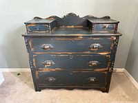 Front view showing three full-width drawers and two top drawers with distressed navy paint and carved pulls