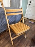 Single wooden folding chair fully opened to show seat and backrest detail.