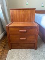 Front view of teak bedside table showing two drawers and top back panel.