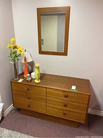 Front view of six-drawer dresser with items on top and mirror mounted above